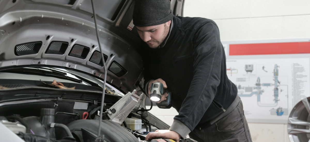 professional mechanic inspecting engine with flashlight