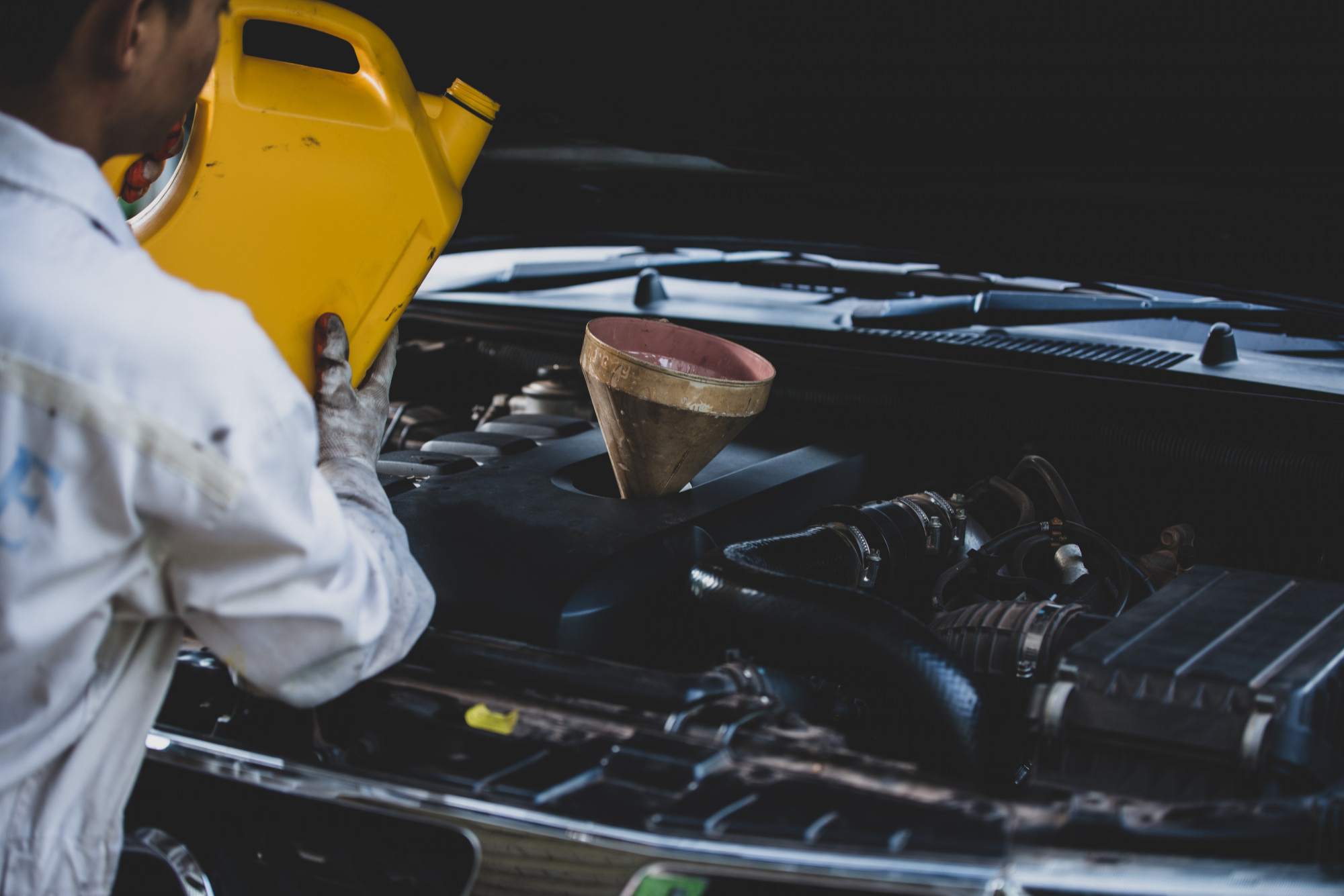 Mechanic pouring engine oil into vehicle