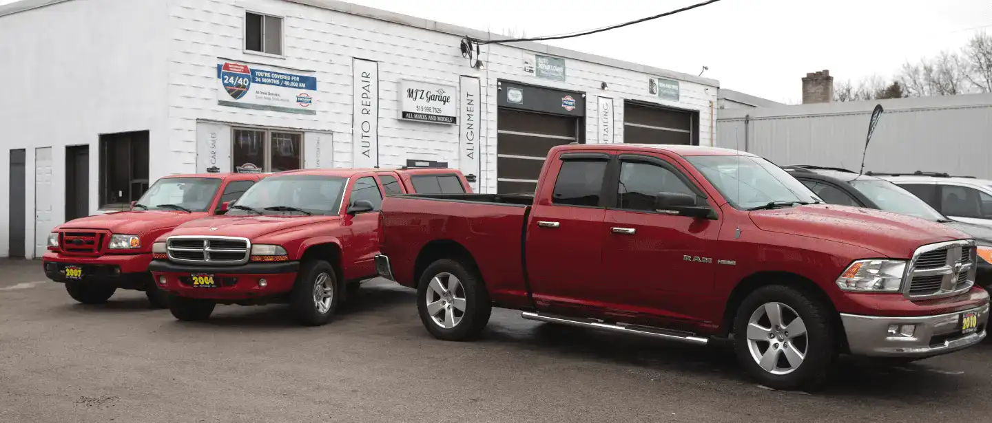 Used trucks and cars parked outside MJZ Garage auto sales in a commercial lot.